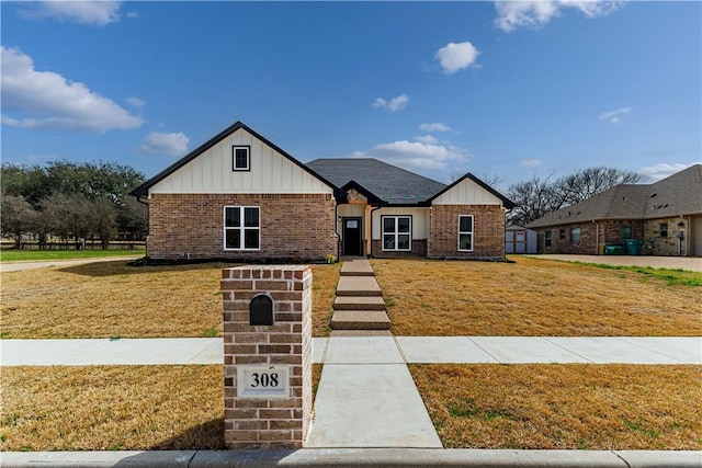 view of front of home featuring brick siding, board and batten siding, and a front yard