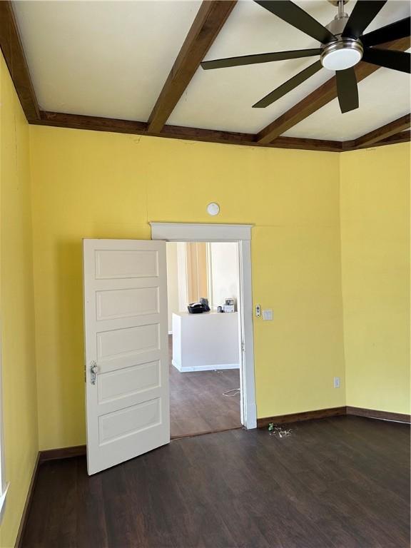 spare room with ceiling fan, beam ceiling, and dark wood-type flooring