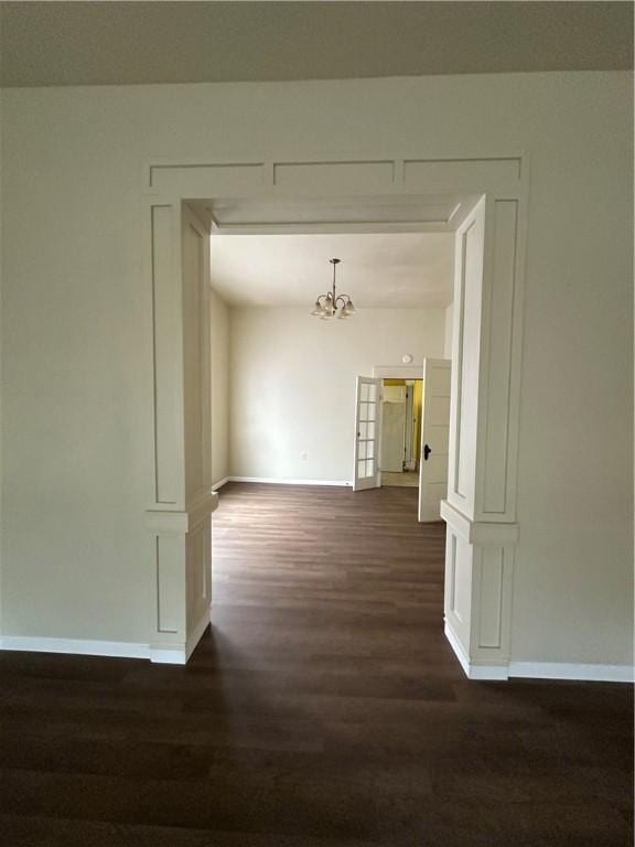 hall with a chandelier and dark wood-type flooring