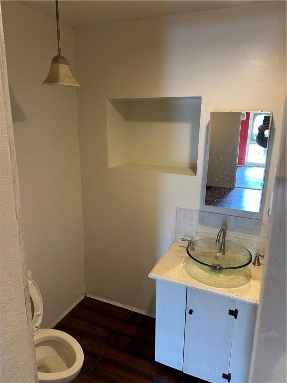 bathroom with decorative backsplash, hardwood / wood-style floors, vanity, and toilet