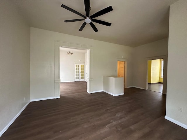 empty room with dark hardwood / wood-style flooring and ceiling fan with notable chandelier