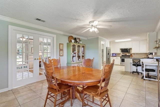 tiled dining space with french doors, a textured ceiling, ceiling fan, and ornamental molding