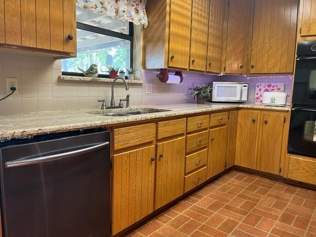 kitchen featuring tasteful backsplash, dishwasher, black double oven, and sink