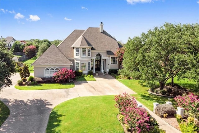 view of front facade featuring a shingled roof, a chimney, a front lawn, and concrete driveway