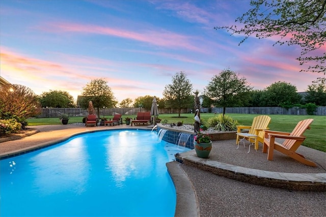 pool at dusk with pool water feature, a yard, and a patio area