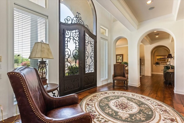 entryway featuring baseboards, arched walkways, ornamental molding, wood finished floors, and french doors