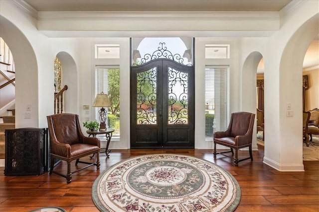 foyer entrance with french doors, dark hardwood / wood-style flooring, and crown molding