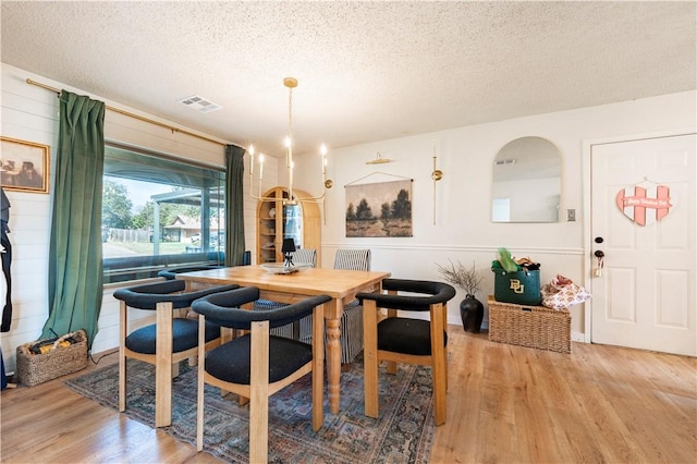 dining room featuring wood-type flooring and a textured ceiling