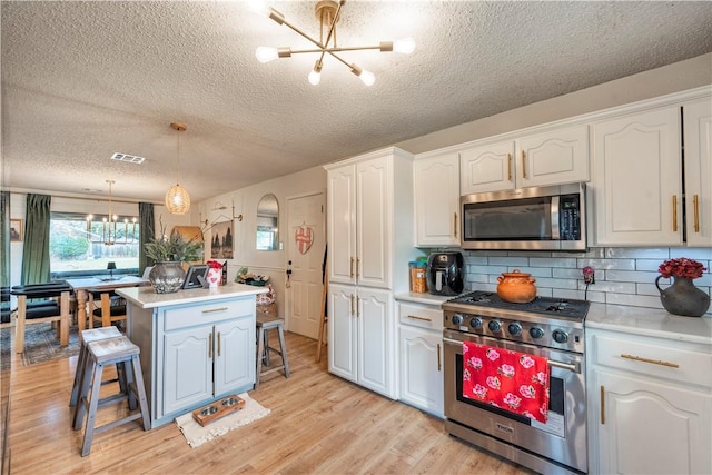 kitchen featuring pendant lighting, stainless steel appliances, a kitchen breakfast bar, a notable chandelier, and white cabinets