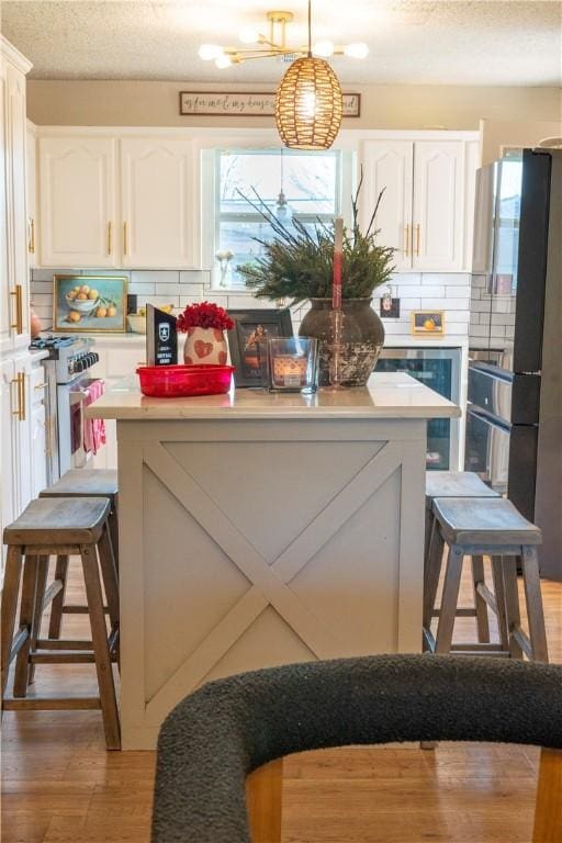 kitchen featuring backsplash, decorative light fixtures, a breakfast bar area, and white cabinets