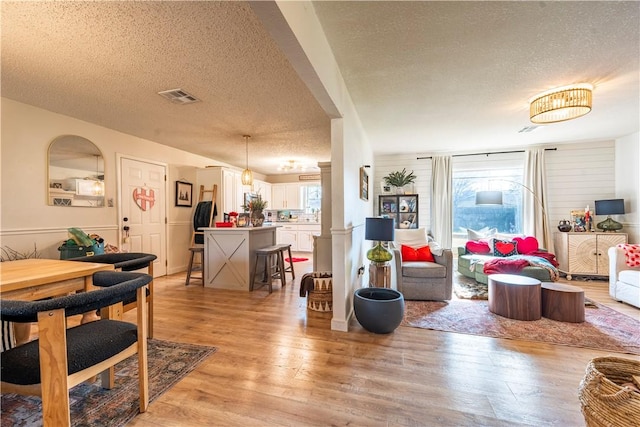 living room with a textured ceiling and light wood-type flooring