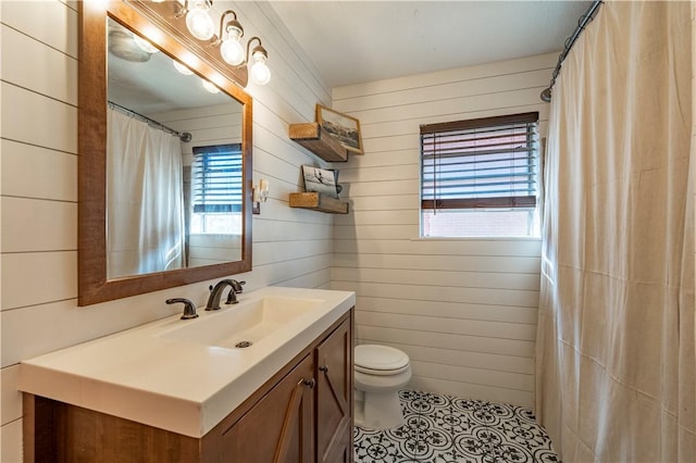 bathroom featuring wooden walls, tile patterned floors, vanity, and toilet