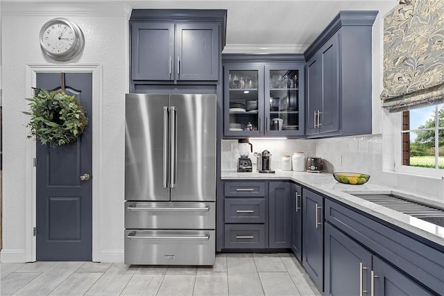 kitchen featuring high end fridge, light stone countertops, crown molding, and tasteful backsplash