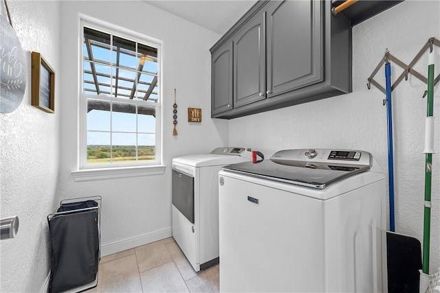 washroom with cabinets, light tile patterned floors, a wealth of natural light, and washing machine and clothes dryer