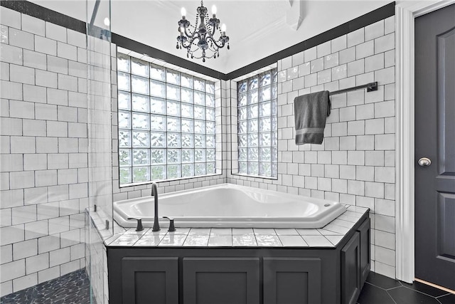 bathroom with tile patterned floors, crown molding, a washtub, tile walls, and a notable chandelier