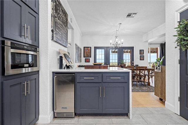 kitchen featuring a chandelier, appliances with stainless steel finishes, light hardwood / wood-style flooring, and ornamental molding