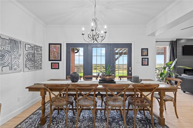 dining space featuring a healthy amount of sunlight, wood-type flooring, ornamental molding, and a chandelier