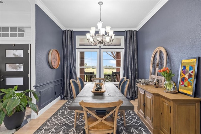 dining area with crown molding, a chandelier, and light wood-type flooring