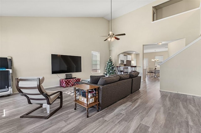 living room featuring ceiling fan with notable chandelier, light hardwood / wood-style floors, and high vaulted ceiling