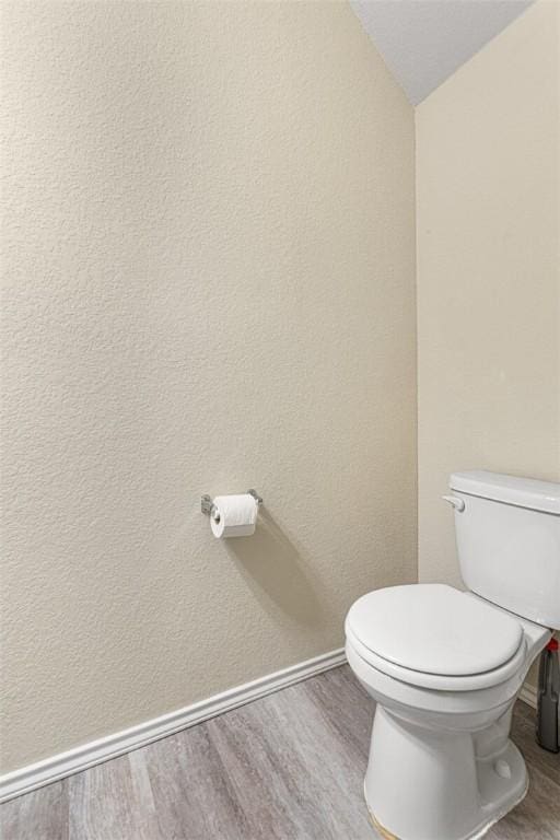 bathroom with toilet, lofted ceiling, and hardwood / wood-style flooring