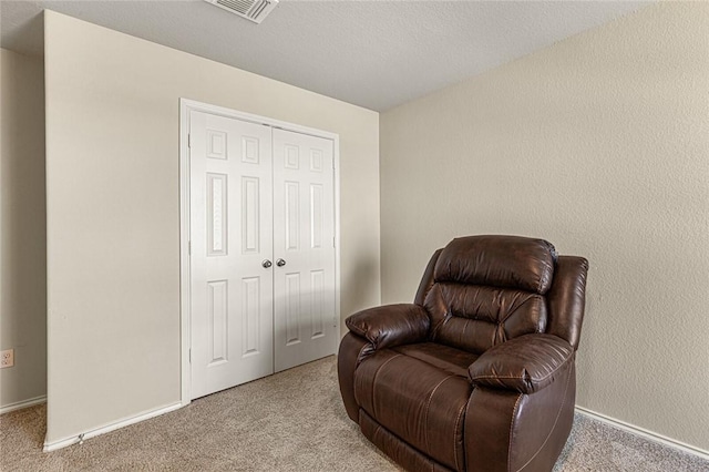 living area featuring light colored carpet and a textured ceiling