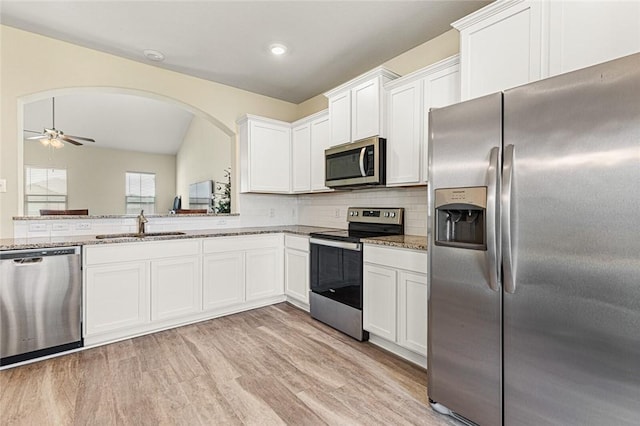 kitchen featuring light stone counters, stainless steel appliances, sink, white cabinets, and light hardwood / wood-style floors