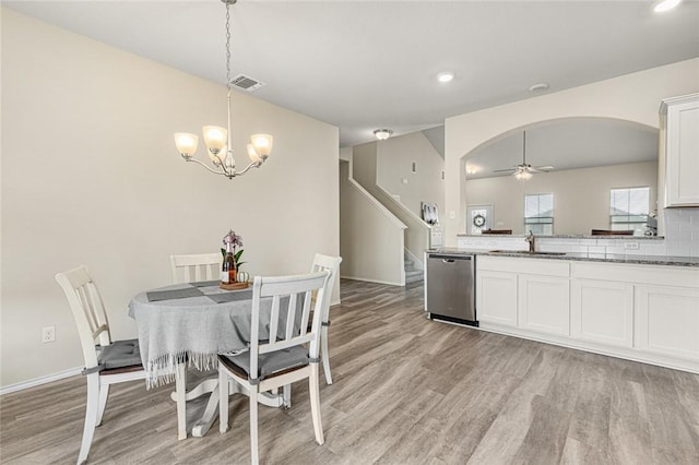 dining room featuring ceiling fan with notable chandelier, light hardwood / wood-style floors, and sink