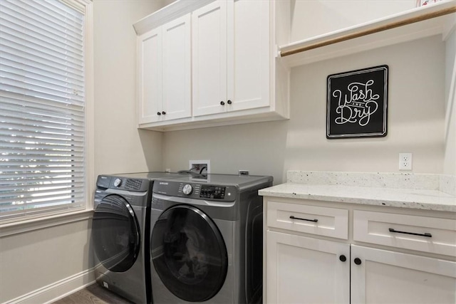 laundry area featuring washing machine and dryer, cabinet space, and baseboards