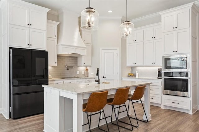 kitchen with appliances with stainless steel finishes, ornamental molding, light wood-style flooring, and custom exhaust hood