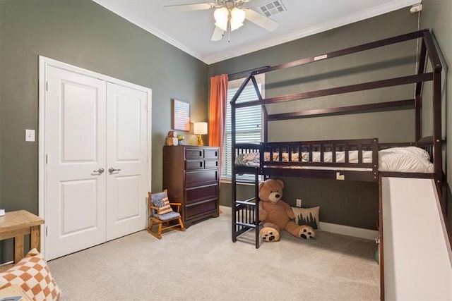 carpeted bedroom with a closet, visible vents, ornamental molding, ceiling fan, and baseboards