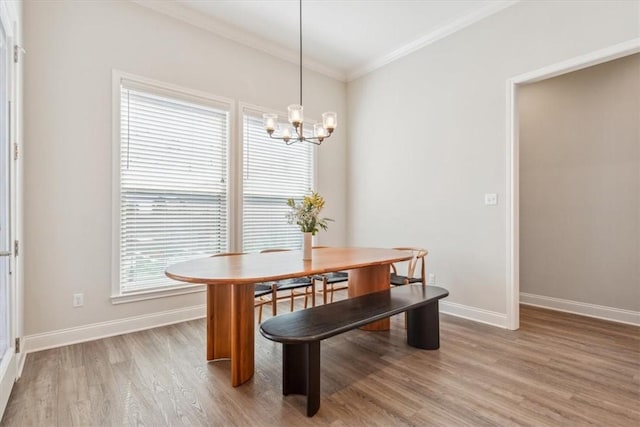 dining space with baseboards, ornamental molding, a notable chandelier, and light wood-style floors