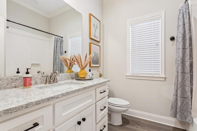 full bathroom featuring baseboards, toilet, ornamental molding, wood finished floors, and vanity