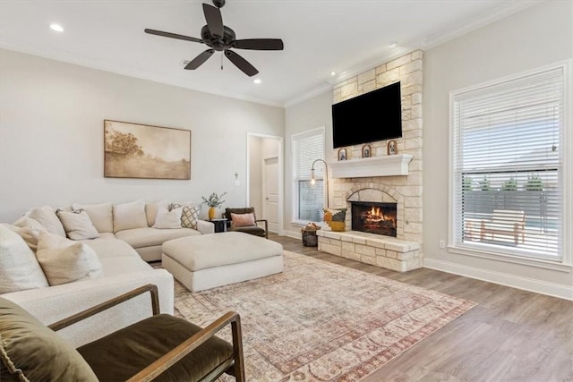 living room featuring a fireplace, baseboards, crown molding, and wood finished floors