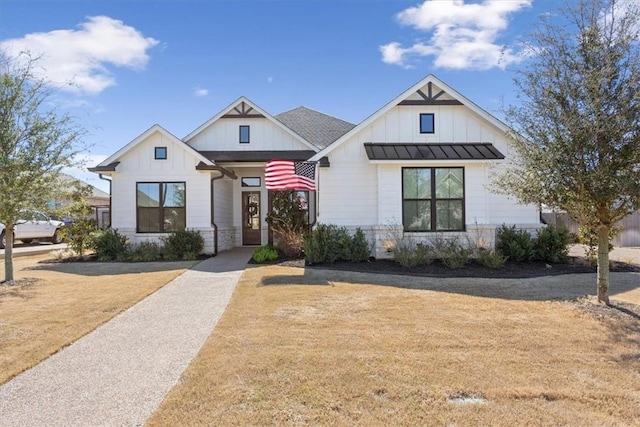 modern inspired farmhouse featuring a standing seam roof, metal roof, a front lawn, and board and batten siding