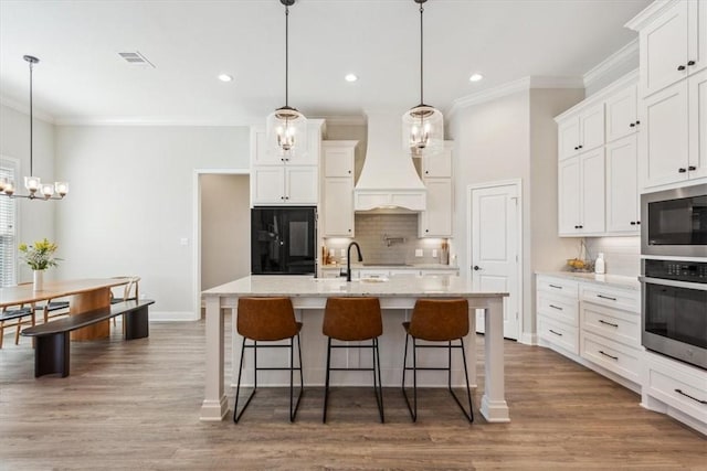 kitchen with crown molding, custom exhaust hood, stainless steel appliances, visible vents, and a sink