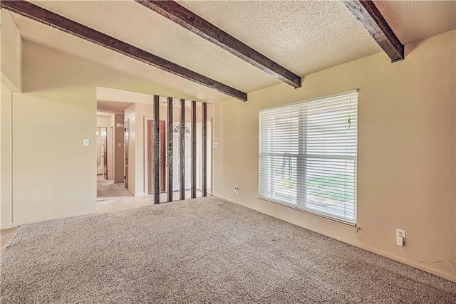 spare room featuring carpet, a textured ceiling, and beamed ceiling