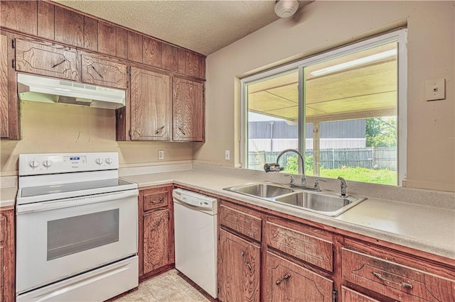 kitchen with a textured ceiling, white appliances, and sink