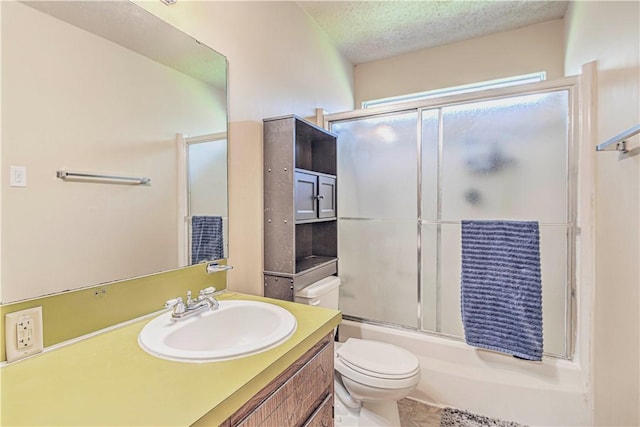 full bathroom featuring vanity, toilet, bath / shower combo with glass door, and a textured ceiling