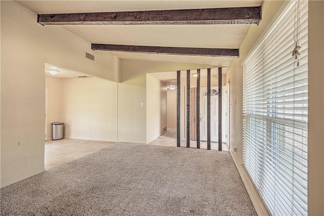 carpeted spare room featuring a textured ceiling and lofted ceiling with beams