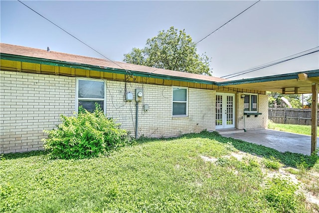 rear view of house featuring a lawn, a patio, and french doors