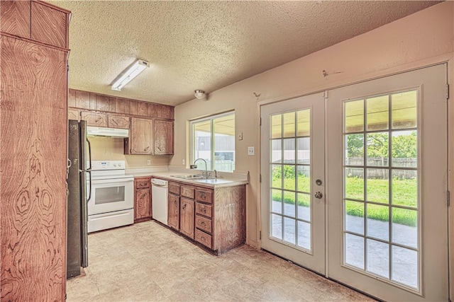 kitchen with a textured ceiling, french doors, white appliances, and sink