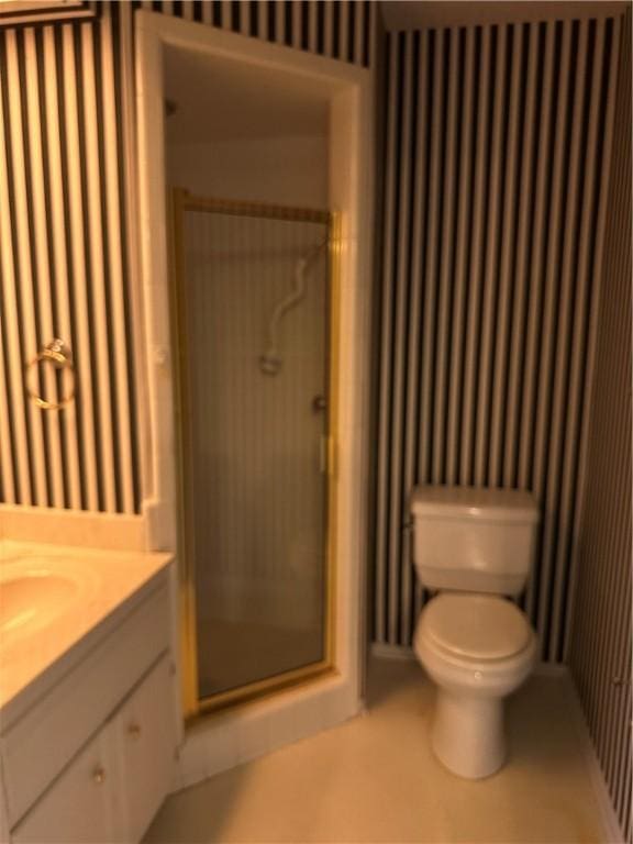 bathroom with vanity, toilet, and a shower with door