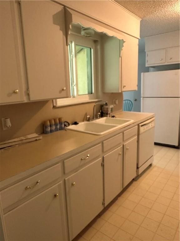 kitchen featuring a textured ceiling, white cabinetry, sink, and white appliances