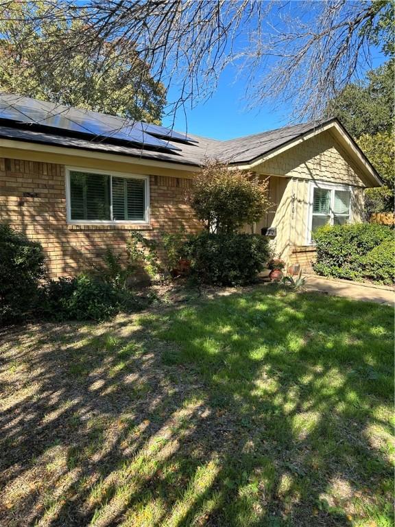 view of side of home with a lawn and solar panels