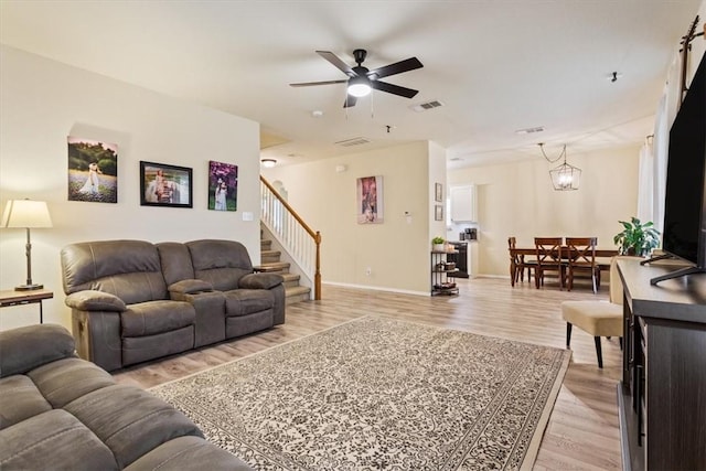 living room featuring ceiling fan with notable chandelier and light hardwood / wood-style flooring