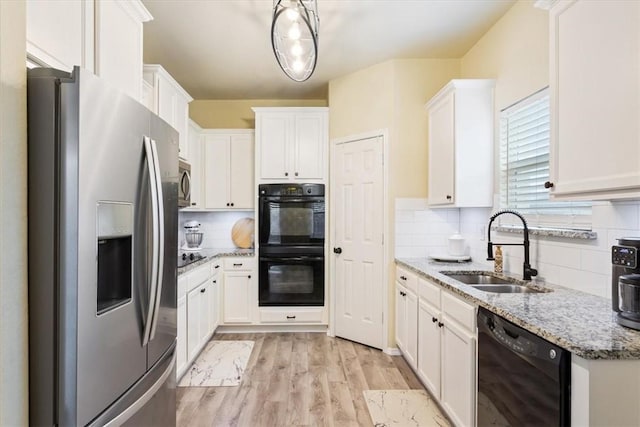 kitchen featuring white cabinetry, sink, light stone counters, backsplash, and black appliances