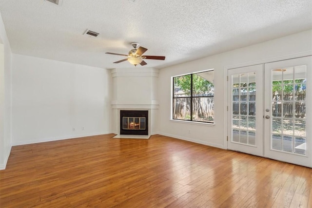 unfurnished living room with french doors, ceiling fan, a textured ceiling, and light wood-type flooring