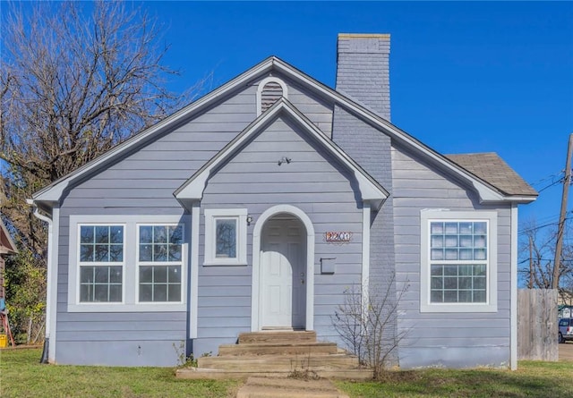 bungalow-style home featuring a front yard and a chimney