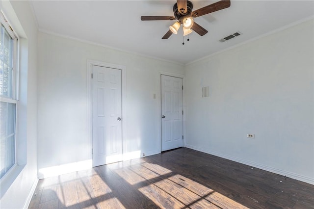 unfurnished bedroom featuring multiple windows, ceiling fan, crown molding, and dark wood-type flooring