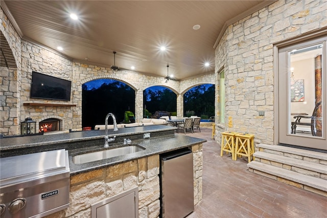 view of patio featuring an outdoor stone fireplace, an outdoor kitchen, and sink